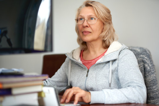 Woman middle aged in glasses using laptop typing email working at home office, lady searching information on internet or communicating online