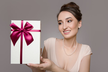 happy woman with a gift. Pink dress. grey background