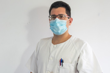 Close-up of a doctor / nurse wearing masks to protect themselves from the covid19. He is wearing a white uniform and glasses.
