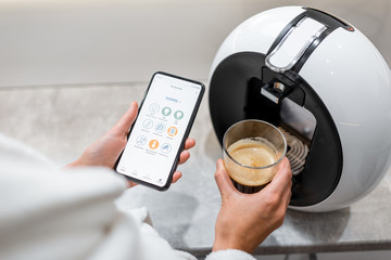 Cotrolling coffe machine with a smart phone, close-up on phone with launched smart home application