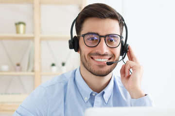 Portrait of office guy working in customer support, wearing glasses and headset, listening to...