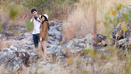 Beautiful Asian couple in love on vacation. Hikers with backpacks relaxing and enjoying view