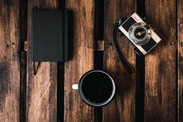 vintage photo camera, notebook and coffee cup on wooden table.