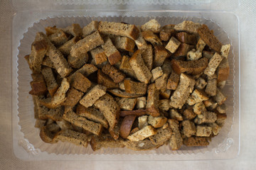 crackers are in a plastic container from the store for salad beer snacks with garlic and cereals from rye bread with seeds