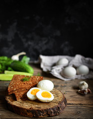 Boiled Chicken Eggs. Healthy breakfast in the village. Wood background. Dark photo. Free space for text. Cucumbers, wooden cutting board.