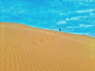 man walking in sand dunes