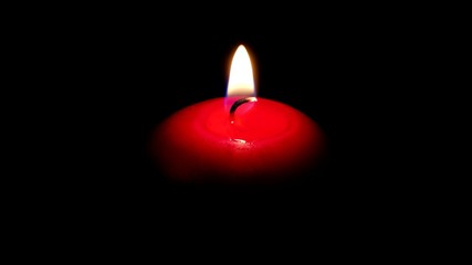 Close-up of a flame of a red canddle in the night