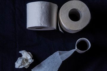 Top view of white toilet paper, single-layer, thin. The paper is on a dark background