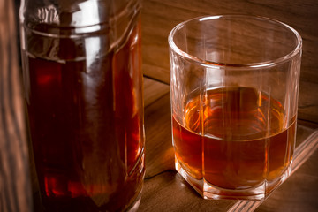 Glass cup and bottle with alcohol on the bar shelf.