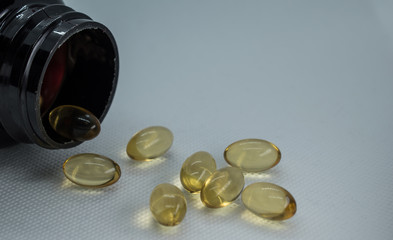 Omega 3 capsules spilling out a bottle on a white background.Fish oil capsules.Healthy supplement...