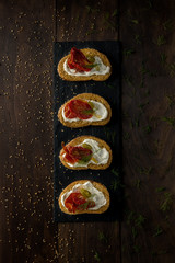 Tapas de queso crema, jamón serrano y jitomate deshidratado sobre madera