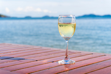 A glass of wine placed on a wooden table by the sea