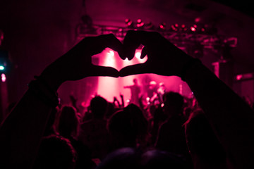 a crowd member holding the love sign up at a concert