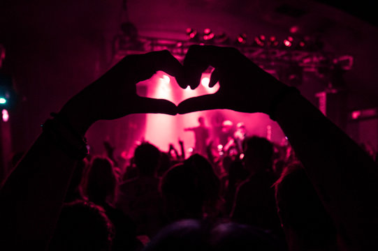 A Crowd Member Holding The Love Sign Up At A Concert