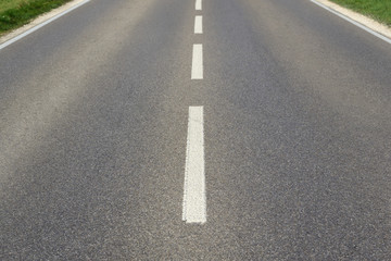 Background with a wide empty paved road and median that stretches from one edge of the picture to the other