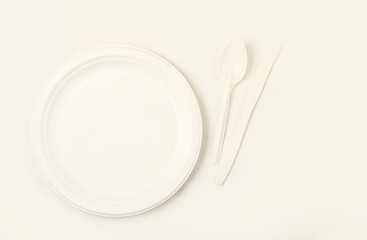 Clean empty plates, cutlery, spoon and knife, on a light background. Eco-friendly biodegradable cookware. Made from corn starch. Ecology concept.