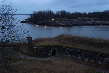 Evening lights of a rocky island and a view of the old fortified old fortified island of Fort Suomenlinna, Sveaborg near Helsinki in Finland in autumn twilight.
