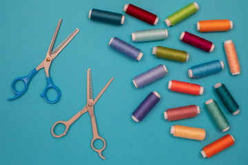 Multicolored cotton threads, spools, scissors, handmade sewing. Top view with copyspace, flat lay.