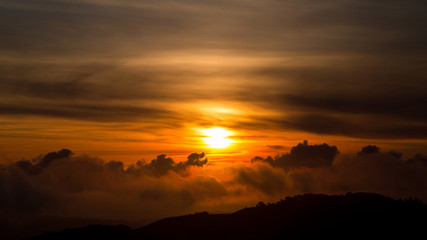 Dark Orange Sunset over Pacific Ocean in California with Dragon Cloud Shape and Hill in Foreground 