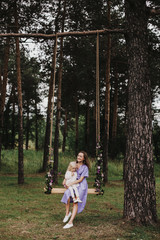 young beautiful mother hugs her little daughter while seeing on a swing in the Park