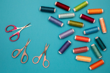 Multicolored cotton threads, spools, scissors, handmade sewing. Top view with copyspace, flat lay.