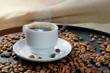 Cup of aromatic coffee and roasted coffee beans, close-up.