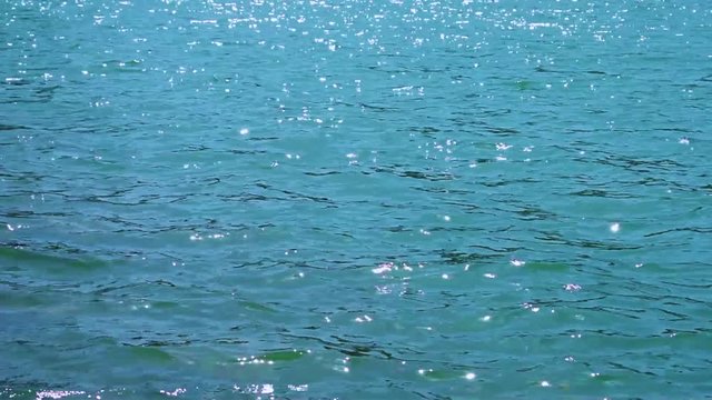Blue beautiful sea waves sparkle in the sun. Motion of water. Summer. Bright shiny background. Natural pattern. Relax, vacation. Reflection. Colorful tropical landscape.
