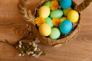 painted eggs in a basket on a wooden background