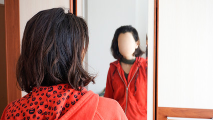 Young woman looking at mirror but can't see her face. Depressed woman don't feel satisfied with her...