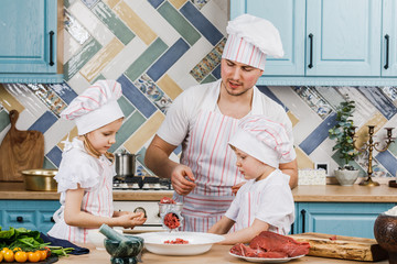 Happy family in the kitchen. Father and children prepare food together in the kitchen at home. The...