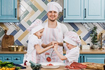 Happy family in the kitchen. Father and children prepare food together in the kitchen at home. The...