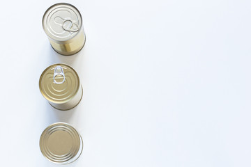 Three cans stand on a white table. Gold, silver. Volunteering