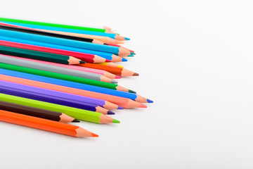 Group of many mixed colourful pencils isolated on a white paper, children school or office suppliers photographed with soft focus from side view, with space for text
