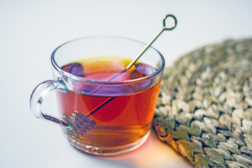 Transparent cup of tea with honey spoon