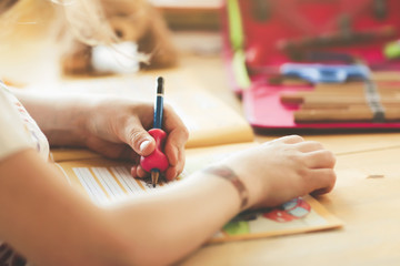 closeup on the hand of a young blonde left-handed girl training her handwriting at home in bright...