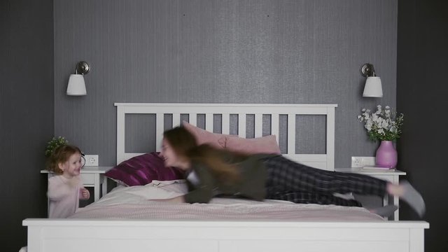Active young mom babysiter and cute little kid daughter playing in bedroom, happy family mother with child girl having fun