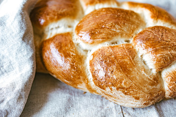 Homemade Jewish traditional challah bread on linen tablecloth. Top view of warm fresh baked challah