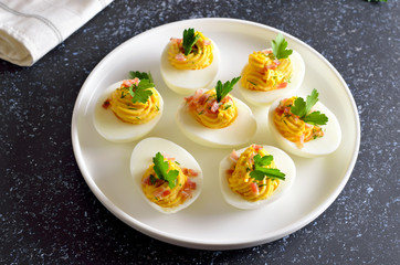 Stuffed eggs with egg yolk, bacon, mustard and parsley