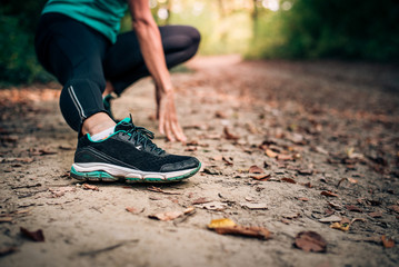 Woman in running shoes stretching leg and warming up before jogging