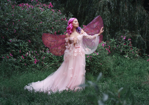 Fairy girl with wings in pinr dress among flowers