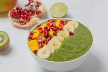 Green smoothie bowl with banana, kiwi, mango and pomegranate. Healthy breakfast