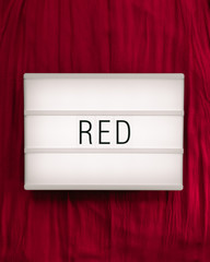 Lightbox with the text "red" on a dark red background; flat lay