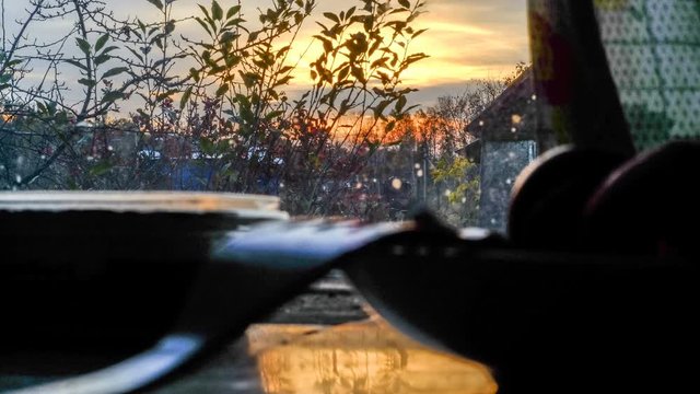 Time lapse on the movement of clouds during sunset in the countryside against the background of wooden buildings and houses in the backlight on a summer evening.
