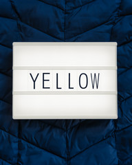 Lightbox with the word "Yellow" on a midnight blue background to express a contrast; complementary, flat lay