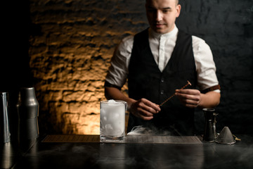 glass with smoky pieces of ice stand on bar