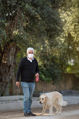 senior man in mask with his pet dog on street because of air pollution and epidemic in city. Protection against virus, infection