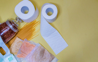 Food items for donation, on a yellow background. Buckwheat in containers for bulk products. Macaroni, cereals in a cellophane bag. With space for text. Vertical photo.