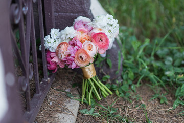 Beautiful white and pink bouquet for a wedding sitting along an iron fence.