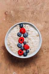 Breakfast oatmeal porridge with fresh berries and almond milk. Healthy vegan food concept. Top view. Copy space. Flat lay
