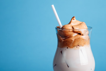 Iced Dalgona Coffee, a trendy fluffy creamy whipped coffee on a bright blue background. new trends in coffee
